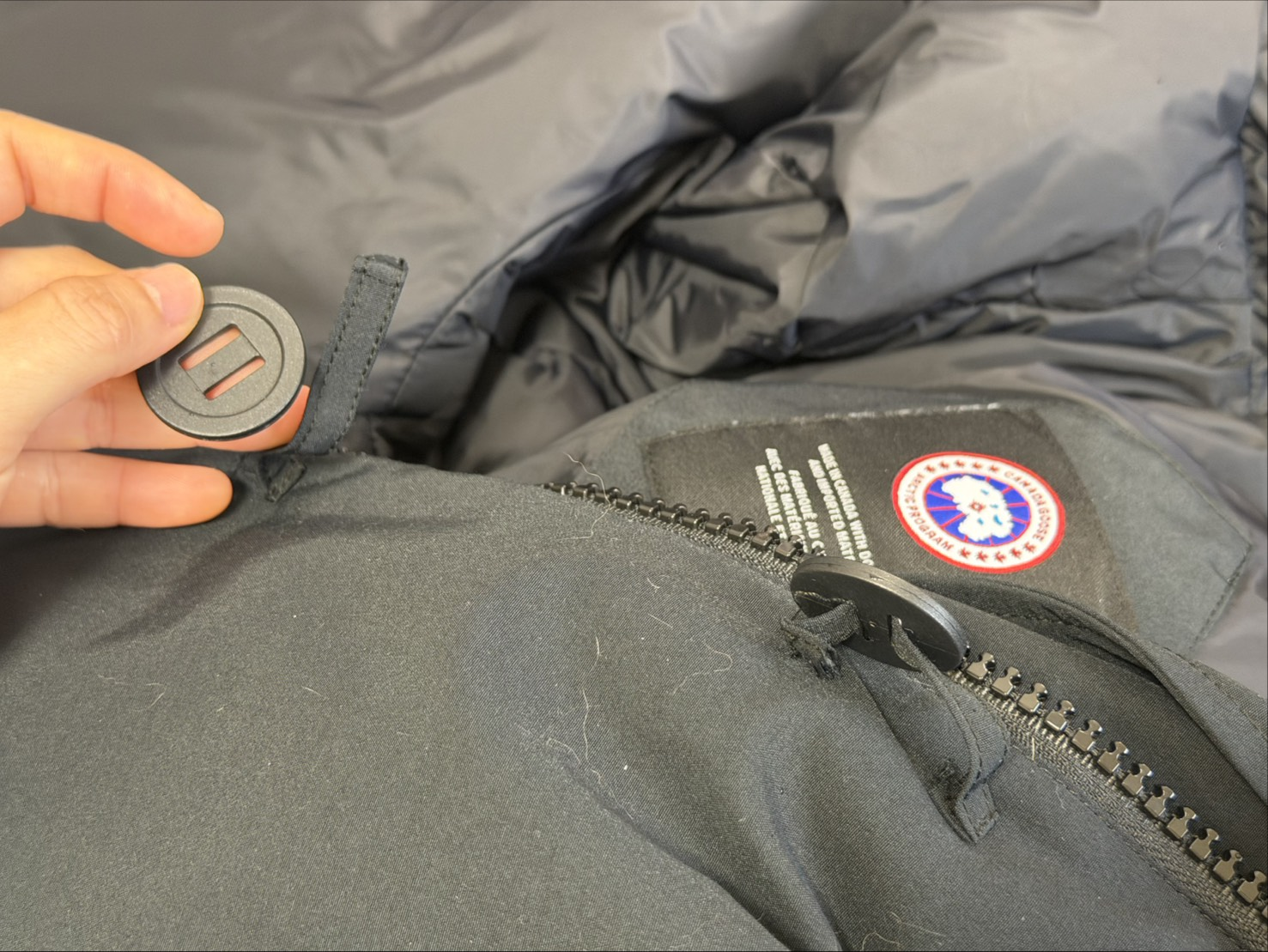 黑色外套上脫落的一顆扣子，和另一顆縫合處也已經脫落一半的扣子