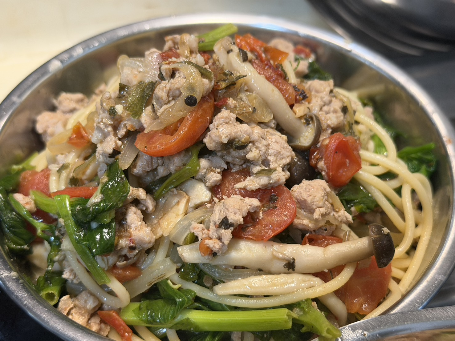 放在不鏽鋼碗裡有肉跟菜跟菇的義大利麵