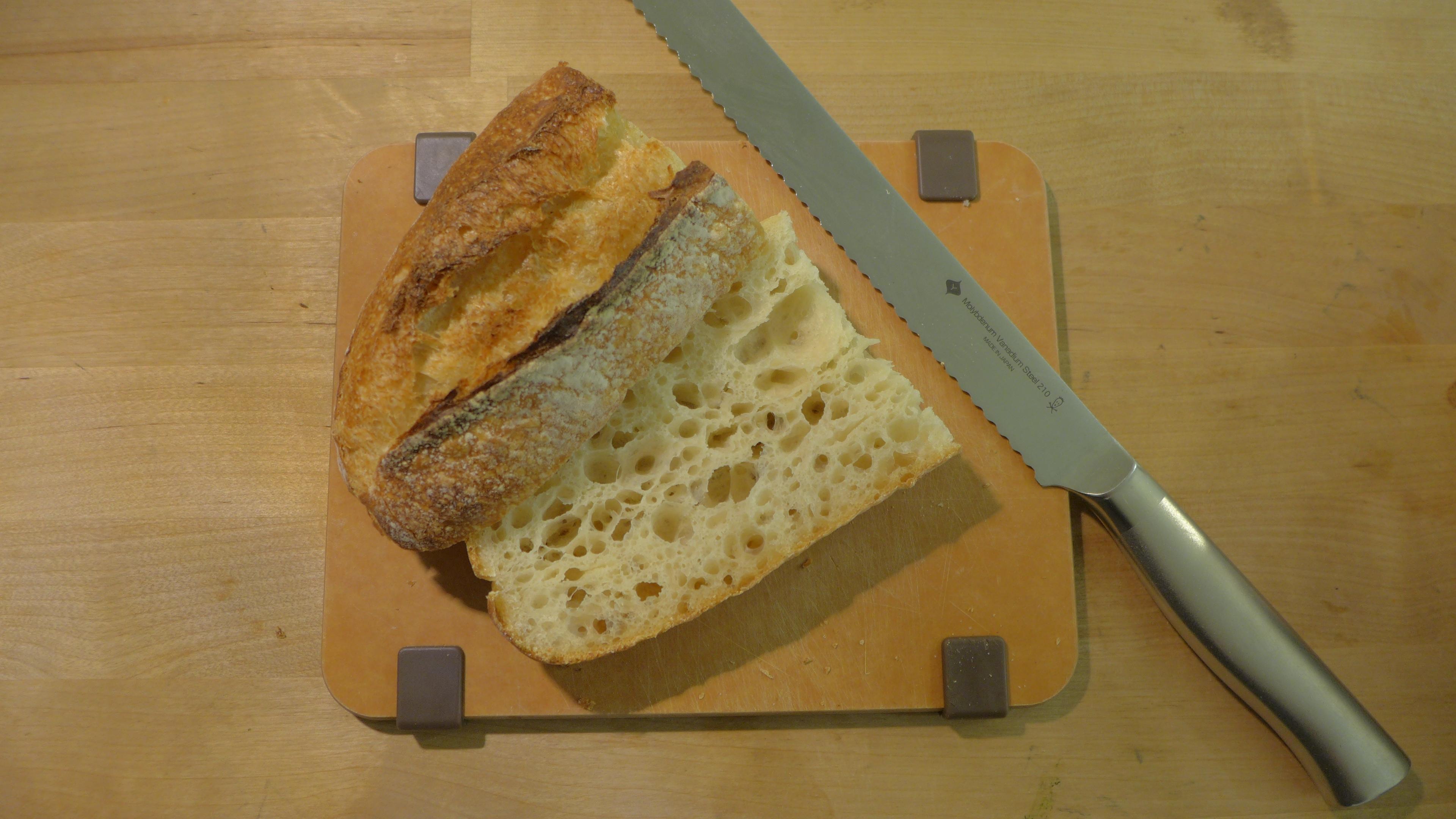 一條左右對半切開後，再從上、下剖開的短法棍麵包，旁邊有一把麵包刀